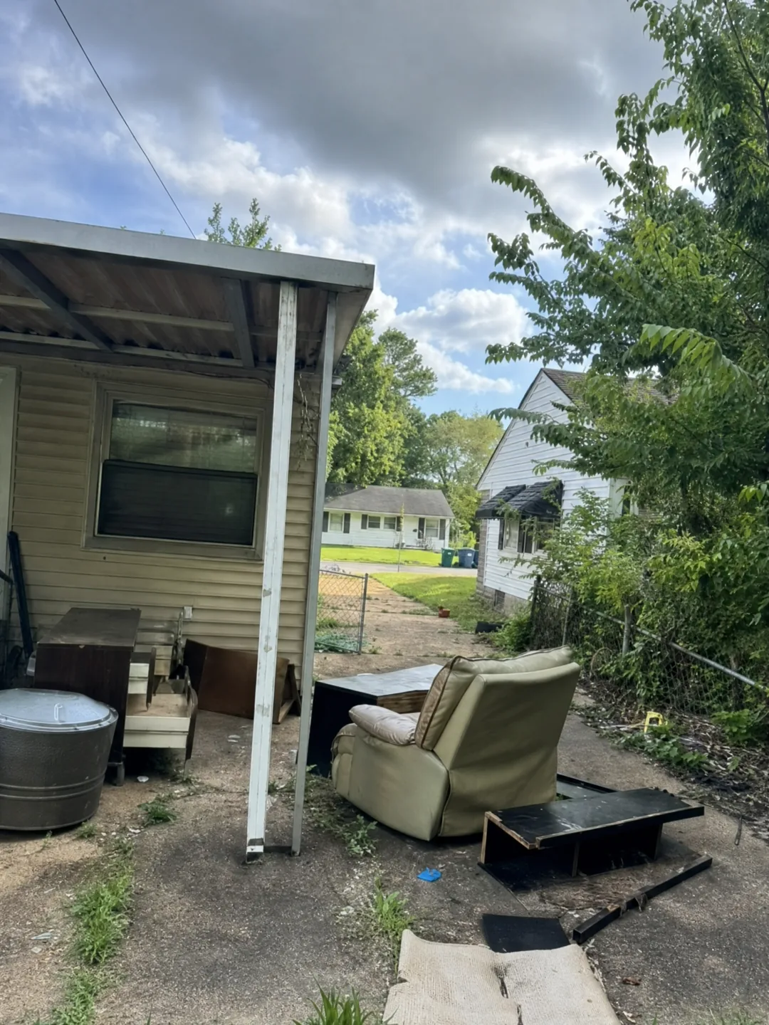 Furniture and household items in a side yard before removal
