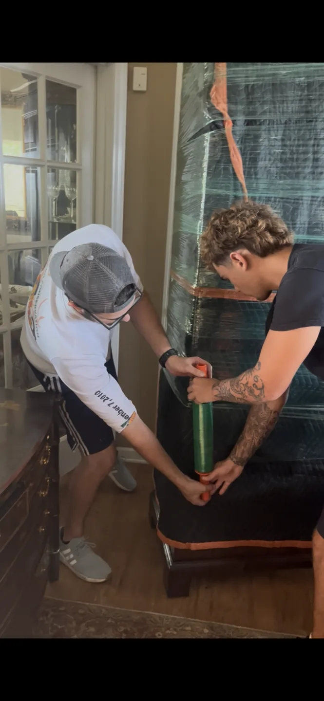 Two One Foot Forward crew members wrapping a blanket-protected furniture item inside a residence